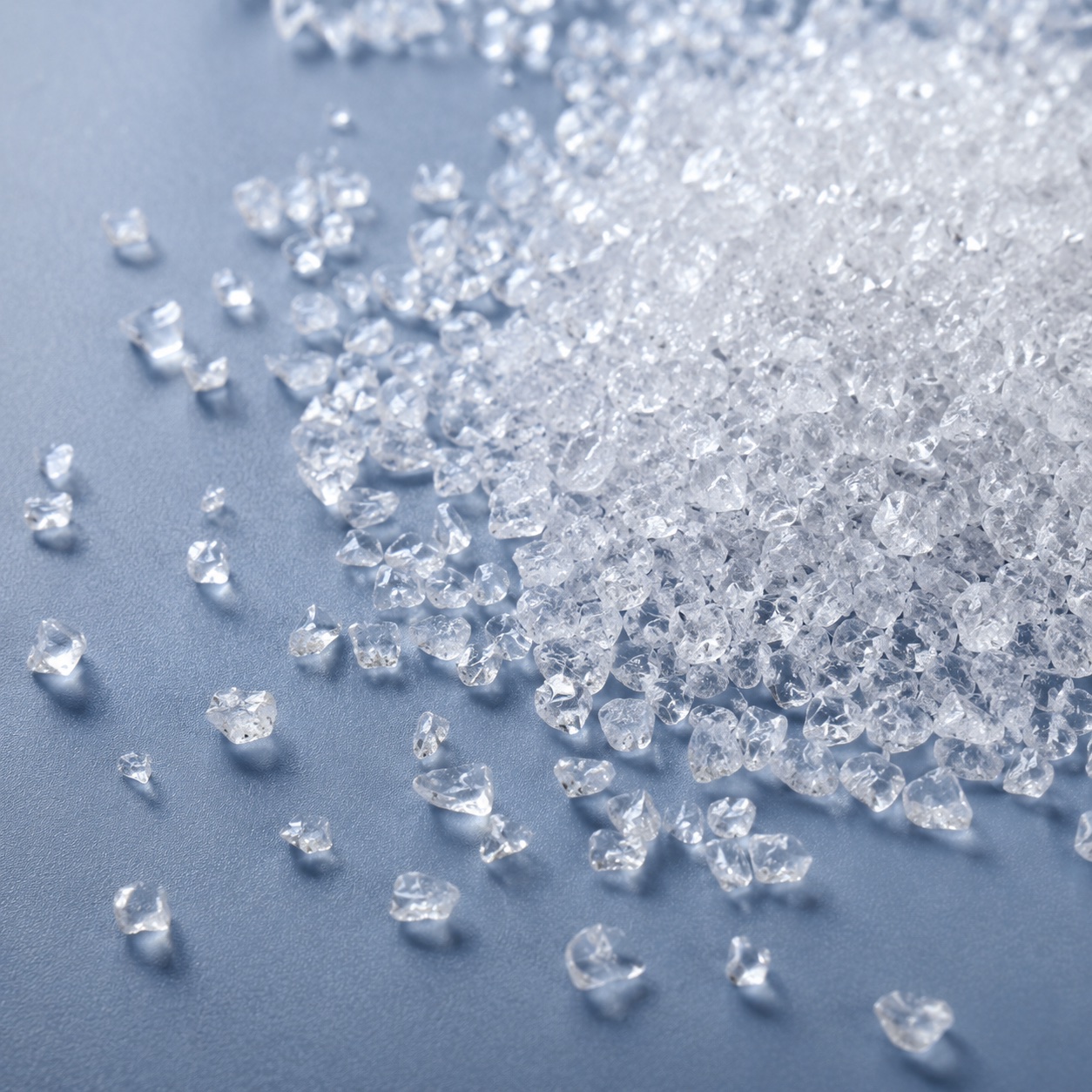 Translucent superabsorbent polymer granules on a blue surface.